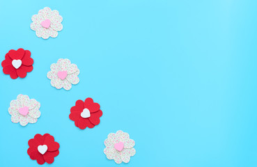 The flowers made of felt hearts on blue background. Mother’s day, Valentine’s day, Wedding, Birthday or other suitable event celebration card concept. Flat lay with copy space for your text.