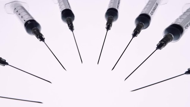 Immunization and treatment from coronavirus. Vaccine and injection. Syringes with needles rotate around the camera. Concept Of Medicine. Medical syringe.