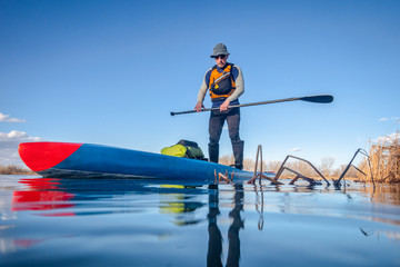 Naklejka premium senior male paddling stand up paddleboard