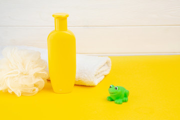 Spa and bath concept. Baby bath set and rubber frog on yellow background.