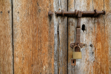 Weathered timber door closed with a latch and a padlock.