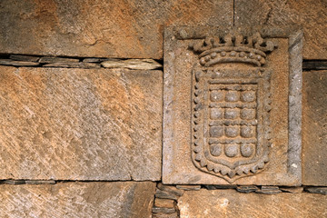 Coat of arms relief in an old wetahred sandstone wall, offset with empty text space on one side.