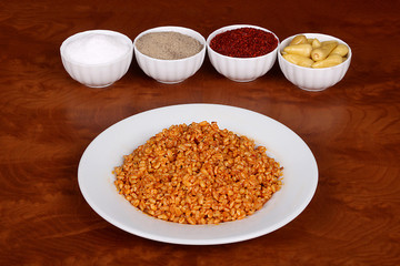 Boiled bulgur with delicious tomato sauce ready to serve on a white plate with special Turkish spices