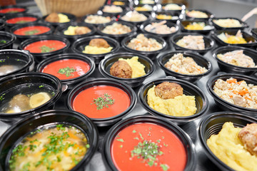 Food delivery. Different in plastic disposable lunch box with healthy natural food. Chicken broth, mashed soup, mashed potatoes with cutlet, seafood pasta, salads, pilaf with a fresh bun.