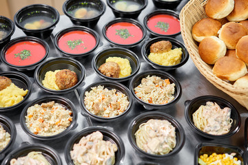 Food delivery. Different in plastic disposable lunch box with healthy natural food. Chicken broth, mashed soup, mashed potatoes with cutlet, seafood pasta, salads, pilaf with a fresh bun.