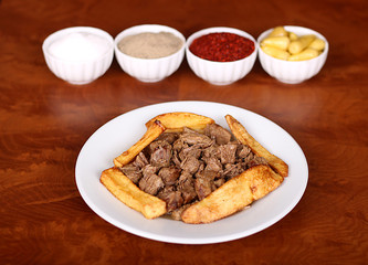 very nice roasting meat with potatoes, turkish spicy on white plate from wooden table close-up