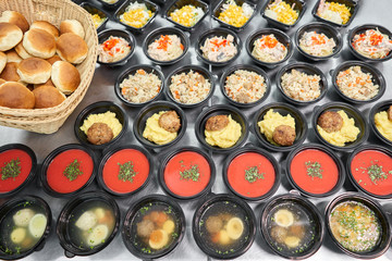 Row of plastic disposable lunch box with healthy natural food. Soups, cream soup, main course with side dish, salads. Food delivery. Lunch in the office.