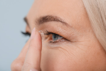 Mature woman putting in contact lenses, closeup