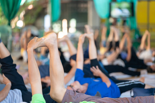 Group of people working out and holding her feet strengthening their at a yoga gym