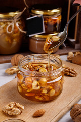Jar of honey on a wooden board. Honey with nuts.