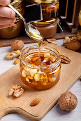 Jar of honey on a wooden board. Honey with nuts.
