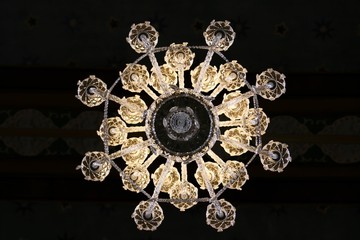 View from below of a chandelier with hanging crystal prisms decor on a church ceiling.