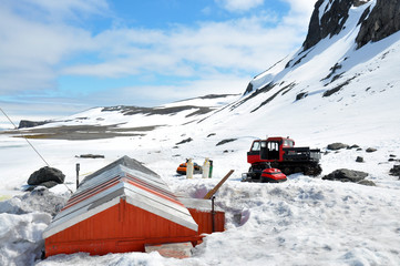 Shelter, snowmobiles and tractor in a sunny day in Carlini base, Antarctica