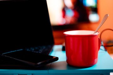 Work from home workspace set-up during Coronavirus pandemic. Red mug, laptop competer,portable hard disk and lap desk