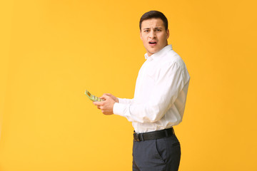 Troubled young man with calculator on color background