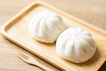 Fototapeta na wymiar Steamed buns stuffed with minced pork on wooden plate with fork ready to eating, Asian food