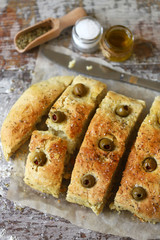 Selective focus. Macro. Fresh homemade focaccia with italian herbs. Cooking at home. Traditional italian bread with olives.