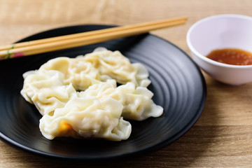 Steamed wonton dumpling stuffed with minced pork and shrimp on black plate and chopsticks, Asian food