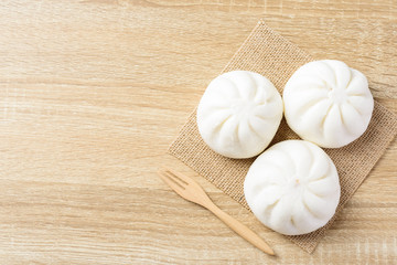 Obraz na płótnie Canvas Steamed buns stuffed with minced pork and fork on wooden background, Asian food, Top view