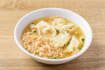 Instant noodles soup and wonton dumpling stuffed with minced pork in a bowl on wooden background, Asian food