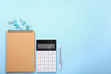 Modern calculator with stationery on color background