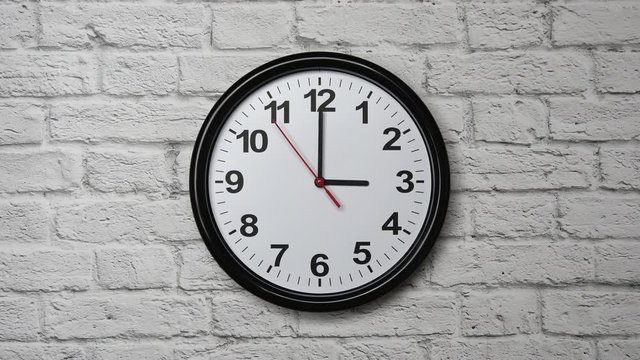 The Time Is 3.00 AM Or PM On A Black Wall Clock With A Red Second Hand On A White Brick Wall.