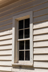 Eight pane window, four over four, in the wall of a clapboard house, vertical aspect