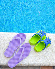 pair of flip-flops by the pool against the blue water.The concept of vacation.