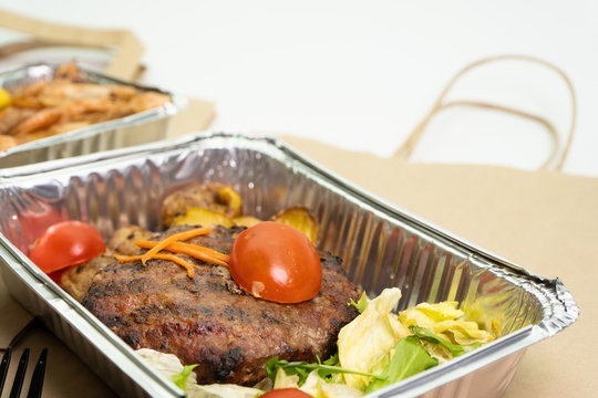 Close-up of a ready meal for delivery and a paper bag on a white background.