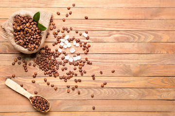 Bag and spoon with coffee beans and sugar on wooden background