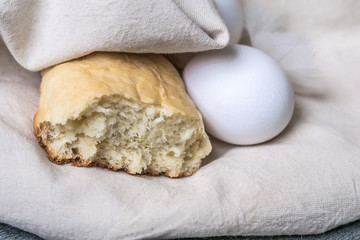 rustic breakfast or a snack with homemade bread and fresh eggs only from chicken in a linen eco bag. macro view and close up on gray stone background