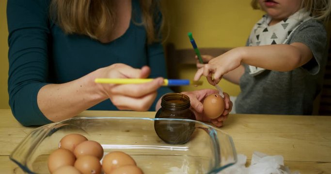 Young mother and preschooler decorating Easter eggs