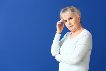 Elderly woman suffering from mental disability on color background