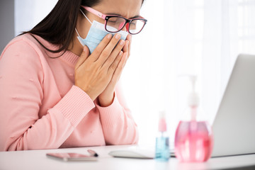 Sick business woman hand taking white tissue paper while cough. Laptop mouse smartphone, sanitizer gel, medical face mask, and alcohol spray for prevention Coronavirus disease (COVID-19).