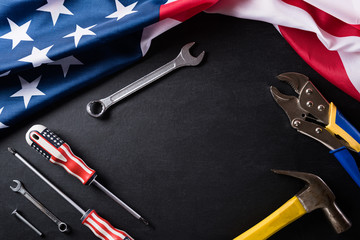 Happy Labor day concept. American flag with different construction tools on black table background, with copy space for text.
