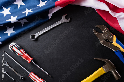 Happy Labor day concept. American flag with different construction tools on black table background, with copy space for text.