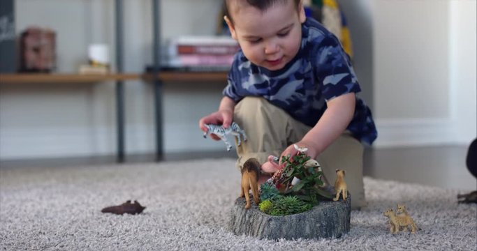 Toddler knocking over toy african animals playing - close up on zeebra and lions