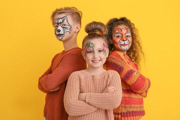 Funny little children with face painting on color background