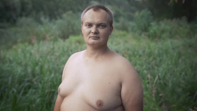 Fat guy looking at the camera on a background of grass