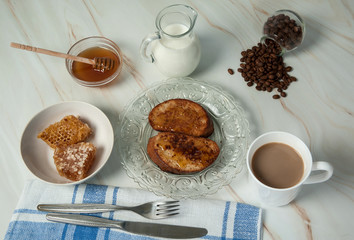 Delicious homemade breakfast. French toast with sweet golden honey, a mug of coffee with milk, a linen napkin and cutlery close-up on a pastel green marble background. Selective focus.