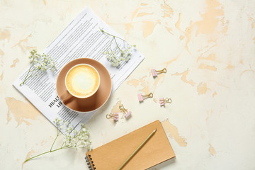 Cup of coffee, notebook, newspaper and flowers on light background