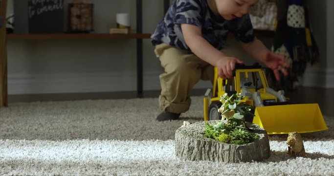 Boy playing with toy animals brings backhoe tractor - destroying habitats