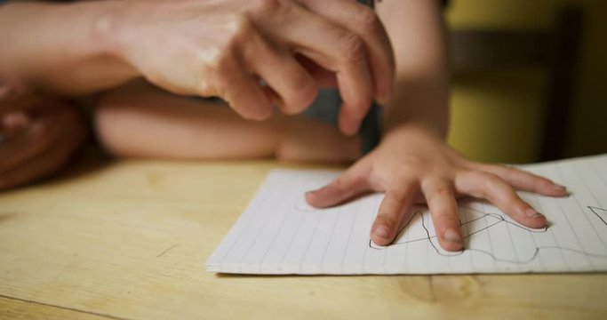 Mother tracing the hand of her preschooler on a piece of paper