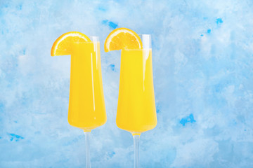 Glasses of tasty mimosa cocktail on color background
