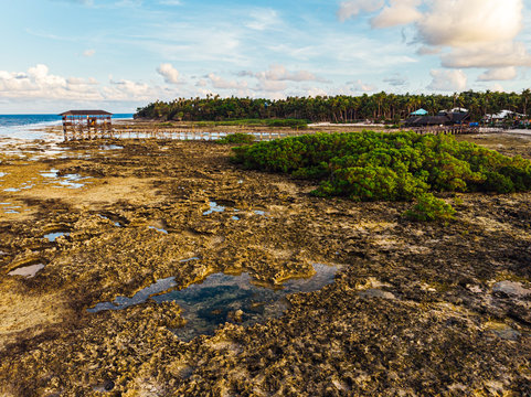 Aerial view of magestic landscape at sunset in the reef of Cloud9 at low tide with coral reef and transparent waters, Siargao Island, Philippines