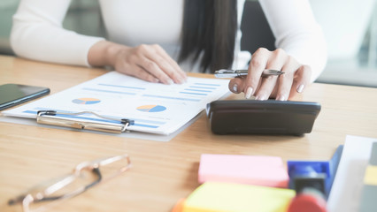 asian businessman or accountant working pointing graph discussion and analysis data charts and graphs and using a calculator to calculate  numbers.Business finances and accounting concept