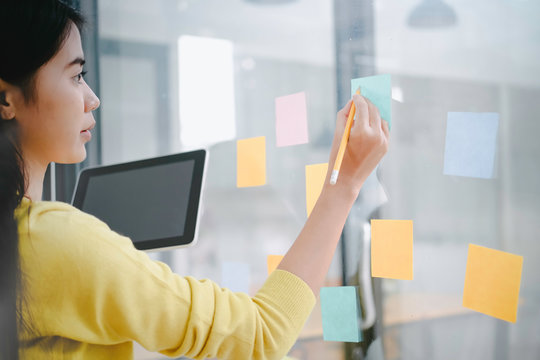 Asian business man hand holding note paper meeting with new startup project use post it notes to share idea discussion and analysis data charts and graphs.Business finances and accounting concept