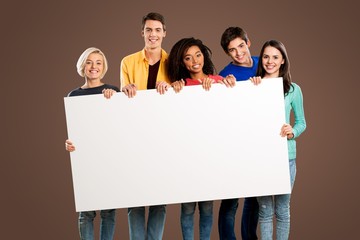 Group of diverse multiethnic happy young people posing with a blank white rectangular sign