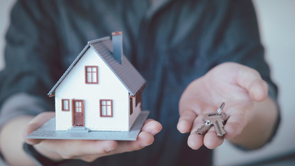 Hands holding small house after signing contract,concept for real estate,Insurance and safety concept with house protected by hands, moving home or renting property