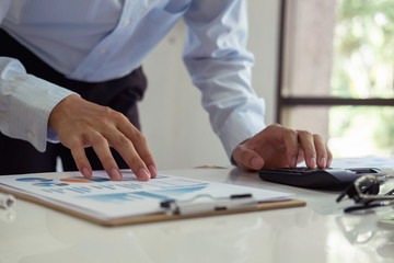 asian businessman or accountant working pointing graph discussion and analysis data charts and graphs and using a calculator to calculate  numbers.Business finances and accounting concept